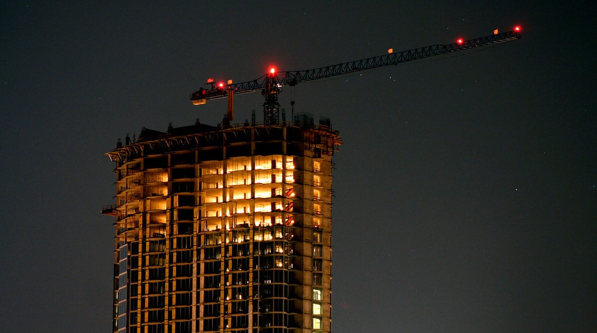 A condo tower under construction at night, illustrative